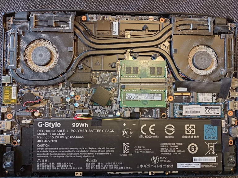 AORUS gaming laptop open with two dusty blower fans and copper cooler