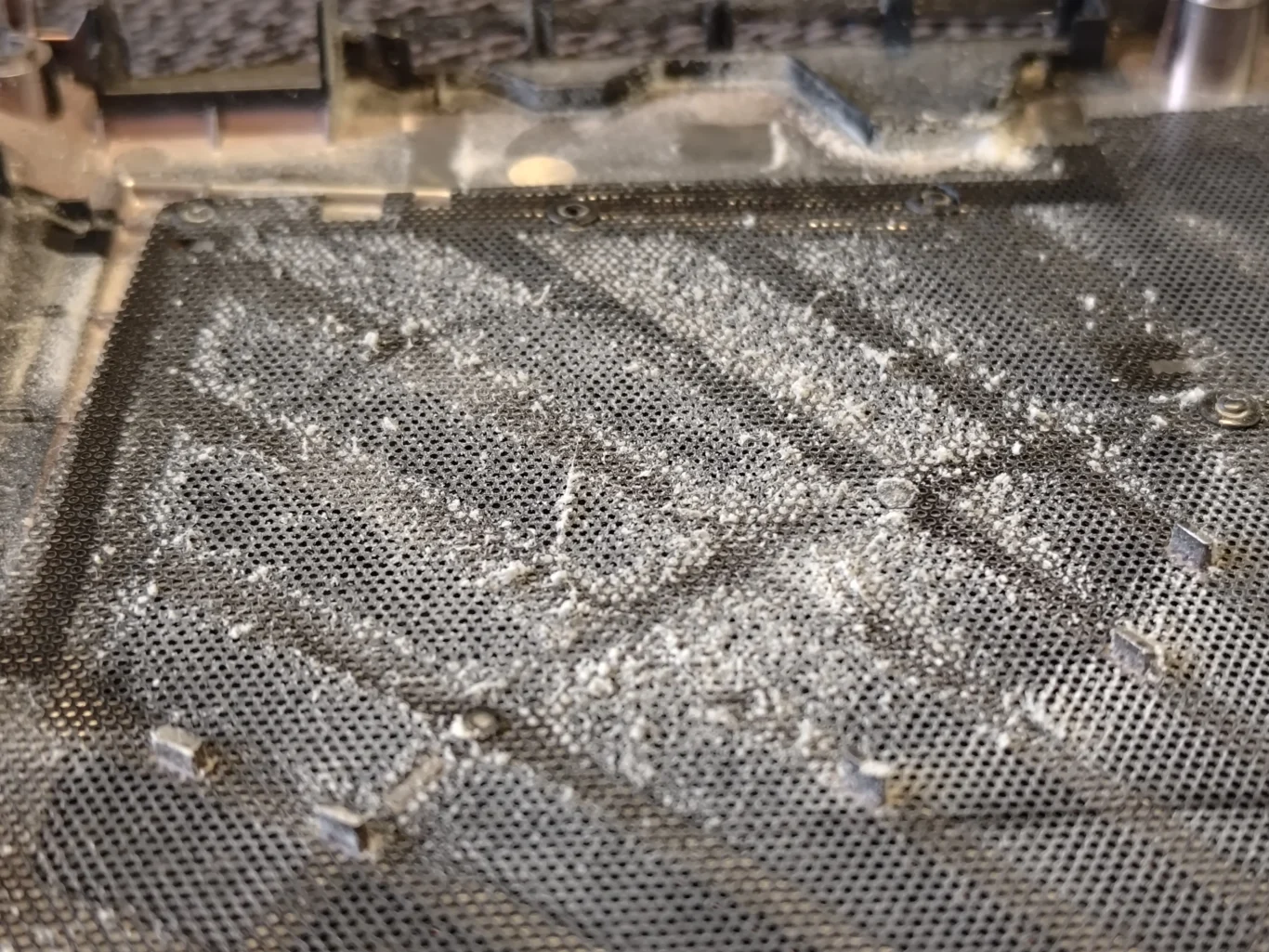 Dust coating the inside of an AORUS laptop lower-cover intake grille