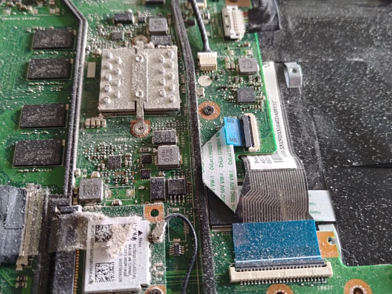 Dust on ASUS R517S motherboard around Wi-Fi module and nearby connectors