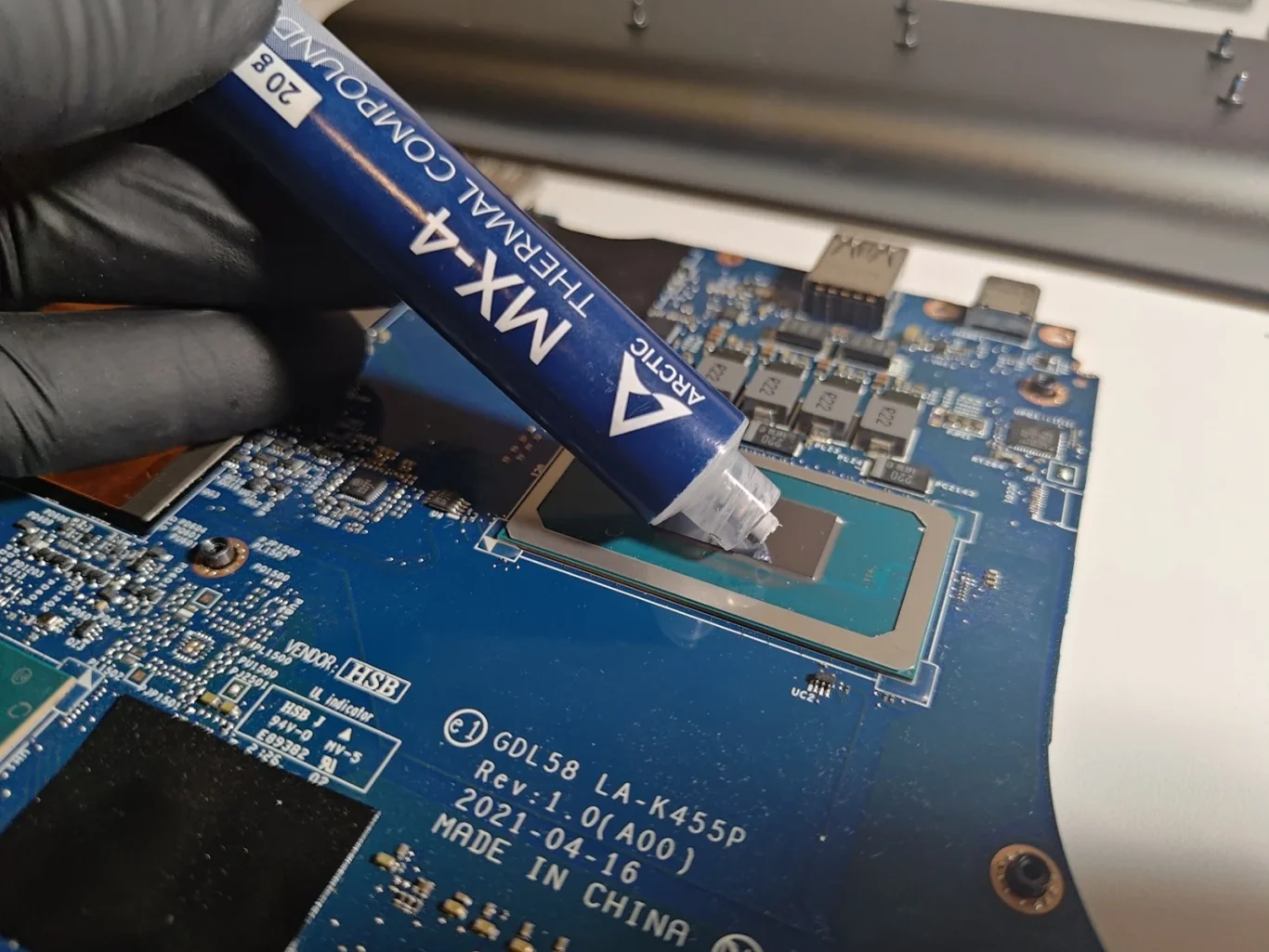 Engineer applying ARCTIC MX-4 thermal paste to the exposed processor of a Dell G15 5511