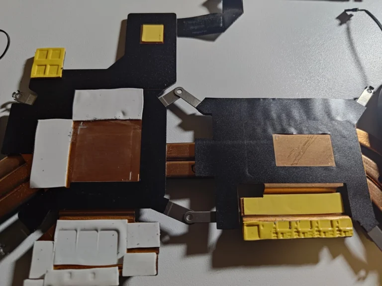 Underside of a Dell G15 heatsink with cleaned copper contact plates and white and yellow thermal pads