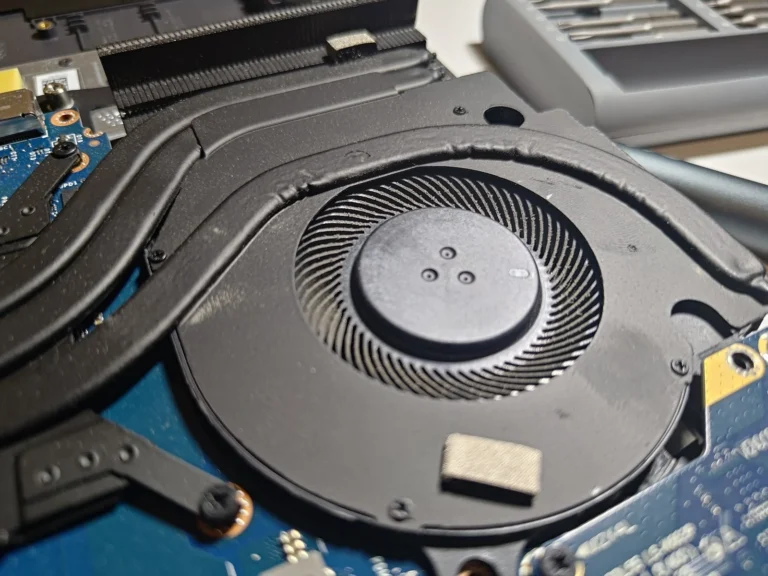 Dell G15 cooling fan beneath black heat pipes, with a row of heatsink fins at the exhaust edge