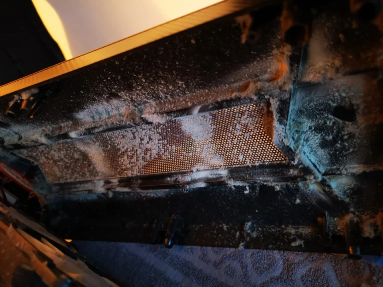 Heavy dust layer on a gaming desktop case intake mesh and inner panel
