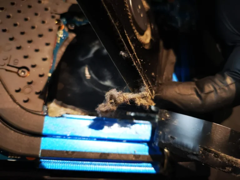 Gloved hand lifting fibrous lint from Helios 300 cooling outlet