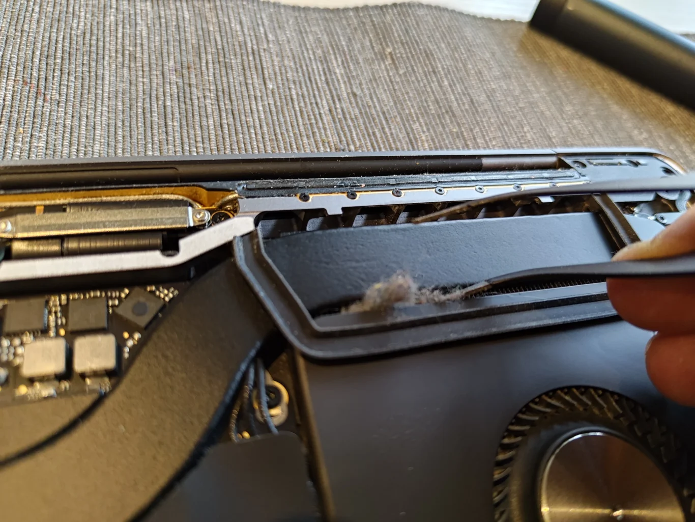 Lint clump lifted from the MacBook Pro A2141 rear outlet beside a fan