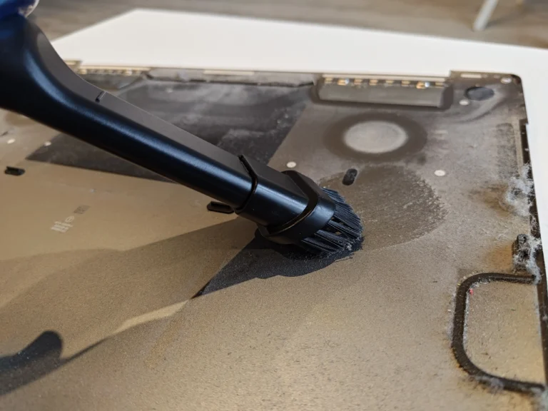 Dust being brushed from the inside of a MacBook Pro A2141 lower cover