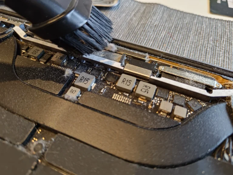 Brush cleaning the rear exhaust channel of an opened MacBook Pro A2141