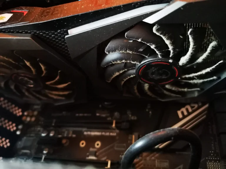 MSI gaming graphics-card fan with lint caught across its blades inside a desktop PC