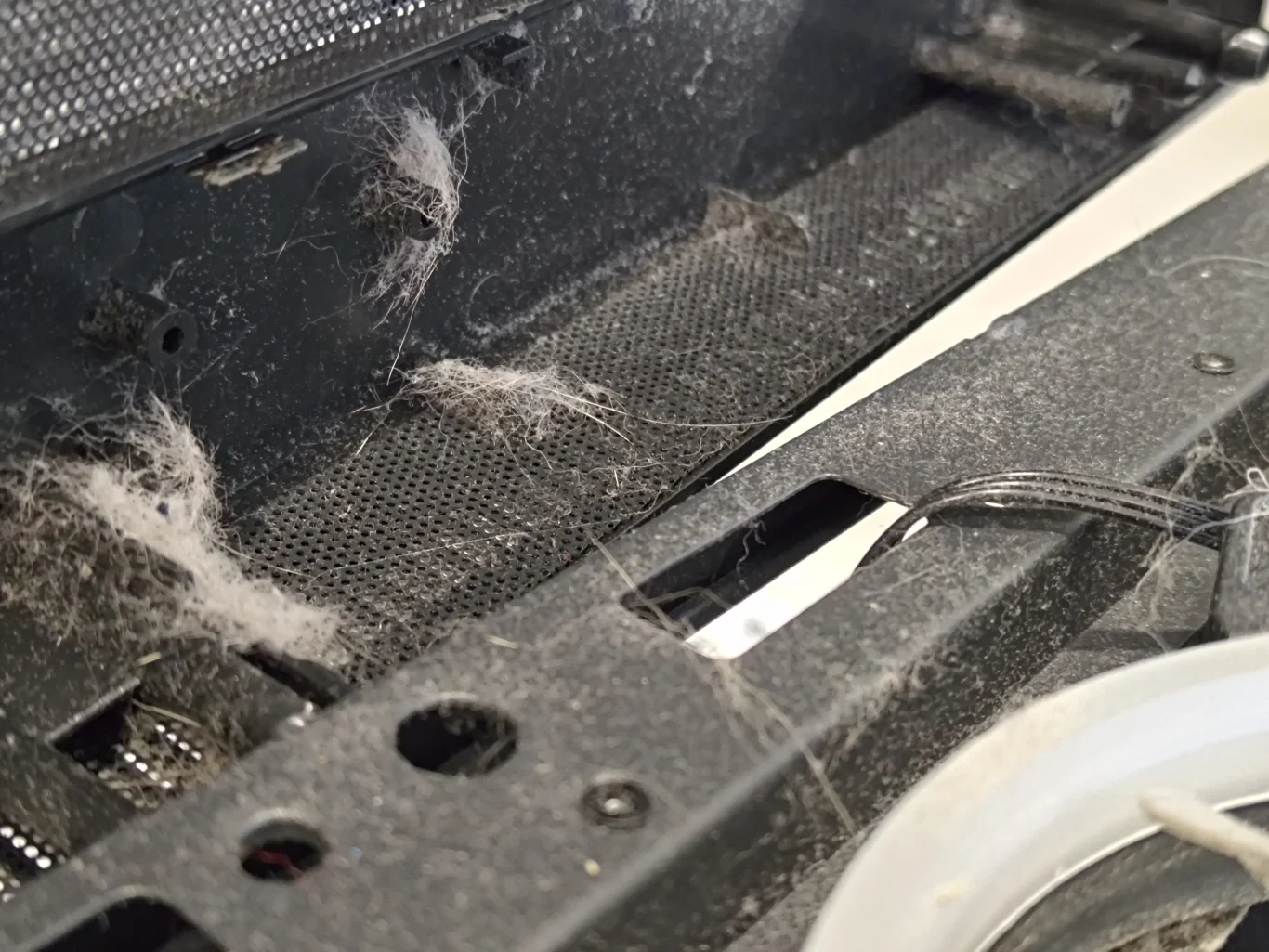 Fibrous lint web across dusty desktop case opening and mesh