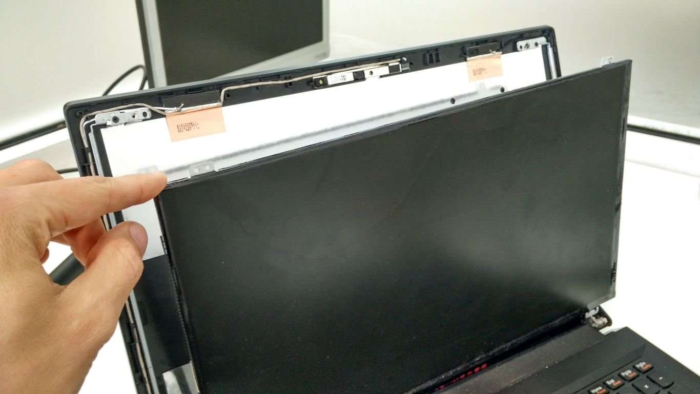 Engineer lifting a damaged screen panel from a laptop